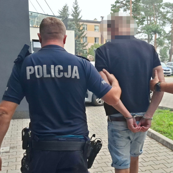 Policjanci prowadzą zatrzymanego 46-latka z dożywotnim zakazem prowadzenia; źródło: otwock.policja.gov.pl