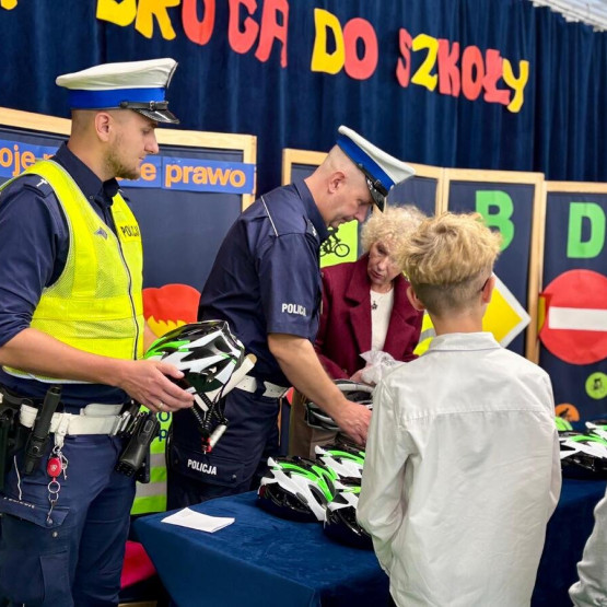 Policjanci przekazują uczniom kaski rowerowe podczas spotkania w Nysie. Źródło: policja.pl, opolska.policja.gov.pl.
