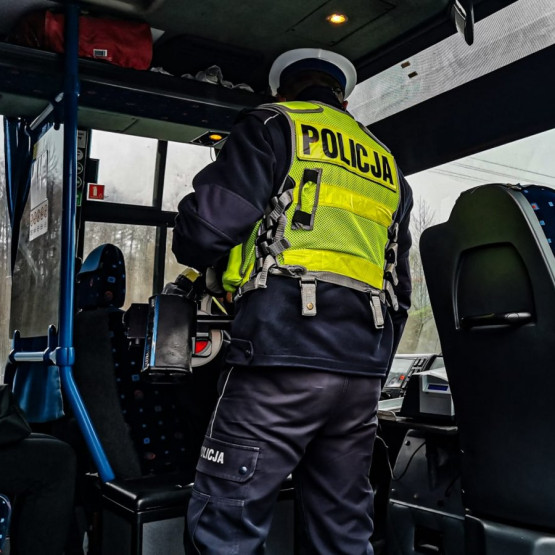 Policjant ruchu drogowego kontroluje wnętrze autobusu przewożącego uczniów. Źródło: hajnowka.policja.gov.pl
