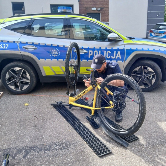 Policjant znakuje rower przy radiowozie podczas akcji w Pilicy i Ogrodzieńcu. Źródło: zawiercie.policja.gov.pl