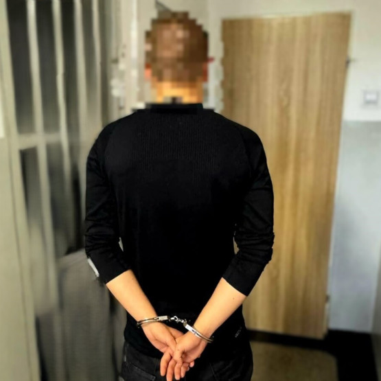 Zatrzymany mężczyzna w kajdankach na korytarzu. Źródło: slaska.policja.gov.pl.