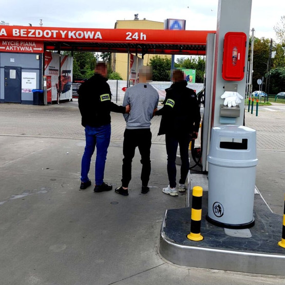 Policjanci prowadzą zatrzymanego na terenie stacji paliw; zdjęcie: slaska.policja.gov.pl