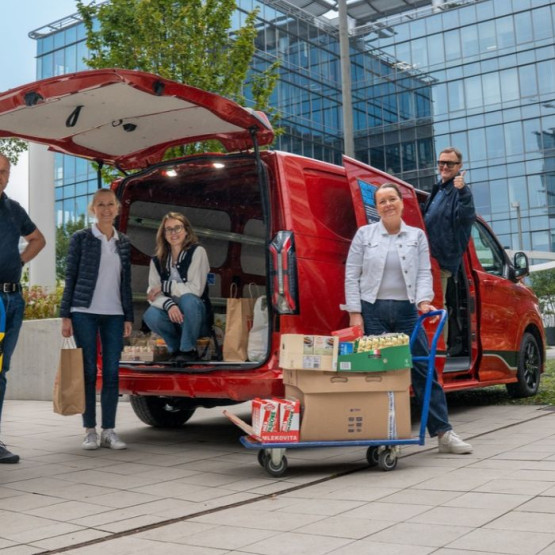 Pracownicy Ford Polska przy samochodzie dostawczym i produktach zebranych dla potrzebujących. Fot. fordmedia.pl